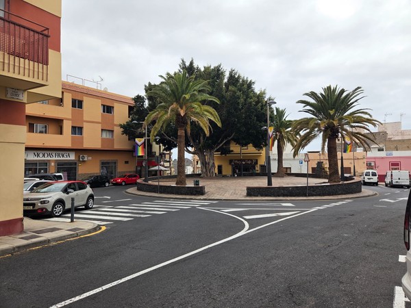 Place circulaire avec des palmiers et des immeubles bas à Adeje, dans un quartier urbain calme sous un ciel nuageux.