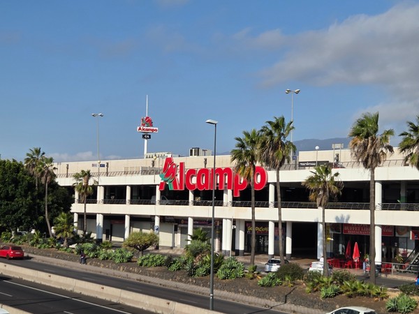 Bâtiment commercial d’Alcampo à La Laguna avec des palmiers devant et l’autoroute TF-5 au premier plan.