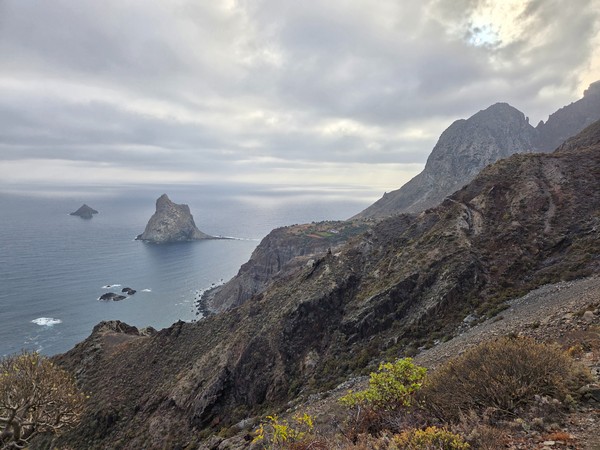 Vue panoramique de la côte nord de l’Anaga avec des falaises, la mer et le Roque de Dentro sous un ciel couvert.