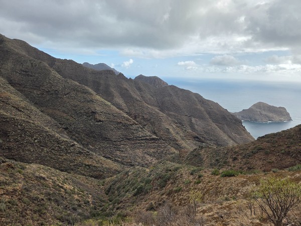 Barranco de Zapata Barranco de Zapata aride avec des pentes volcaniques, des nuages bas et une petite baie visible au fond.