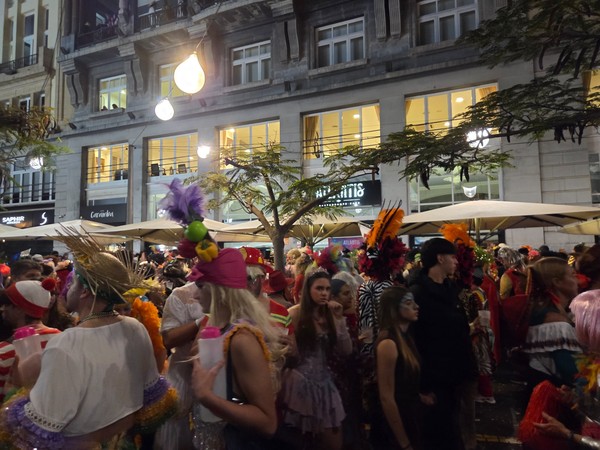 Ambiance du carnaval de Santa Cruz de Tenerife avec une foule costumée dans une rue animée en soirée.