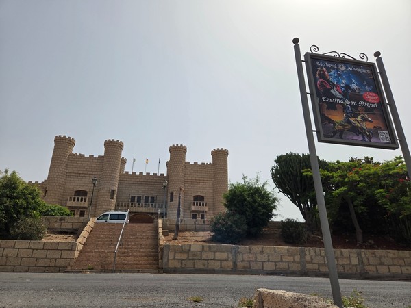 Façade du Castillo San Miguel à Tenerife avec ses tours, son escalier et un panneau du spectacle Medieval Adventure.