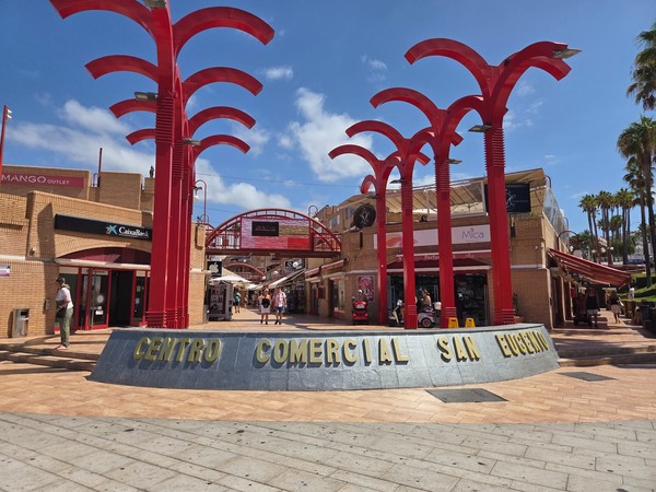 Entrée du centre commercial San Eugenio à Costa Adeje avec ses structures rouges caractéristiques et ses boutiques autour.