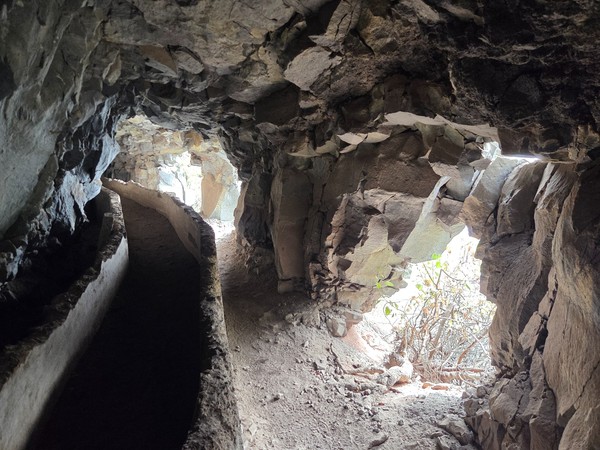 Intérieur d'une grotte volcanique à Güímar avec un ancien canal d'eau et des ouvertures laissant entrer la lumière.