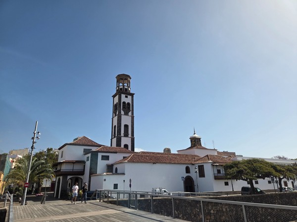 Église de la Concepción avec son clocher élancé, ses murs blancs et un pont piéton au premier plan.