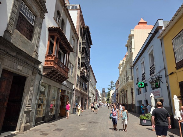 Rue de La Laguna Rue piétonne de La Laguna avec façades historiques, balcons en bois et passants sous un ciel dégagé.