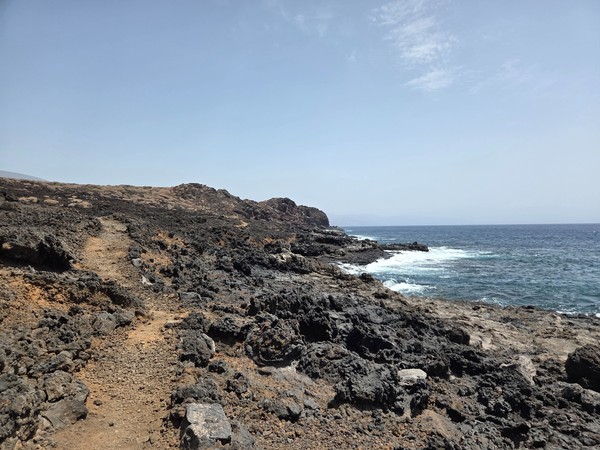 Sentier volcanique du Malpaís de Güímar longeant une côte rocheuse battue par l’océan.