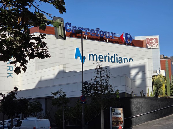 Façade du centre commercial Meridiano à Santa Cruz de Tenerife avec les enseignes de Carrefour et de Yelmo Cines par une journée ensoleillée.