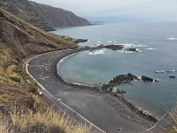 Vue en hauteur de Playa Arenas del Mar à Tenerife, montrant une baie de sable noir, une promenade courbe et une mer calme.