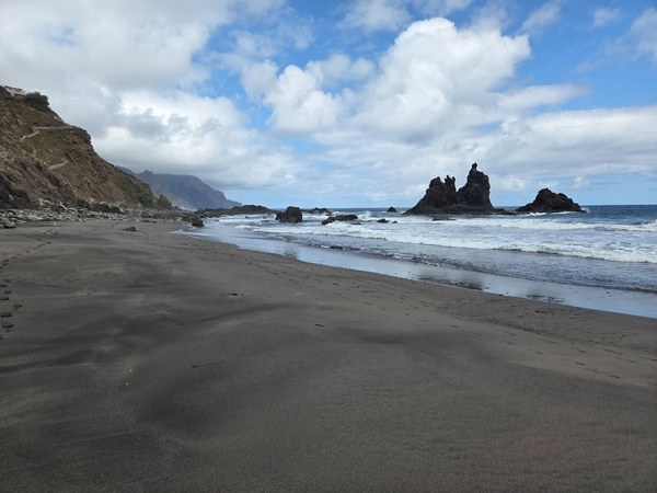 Plage de Benijo à Tenerife avec vaste sable noir, mer agitée et formations rocheuses emblématiques au large.