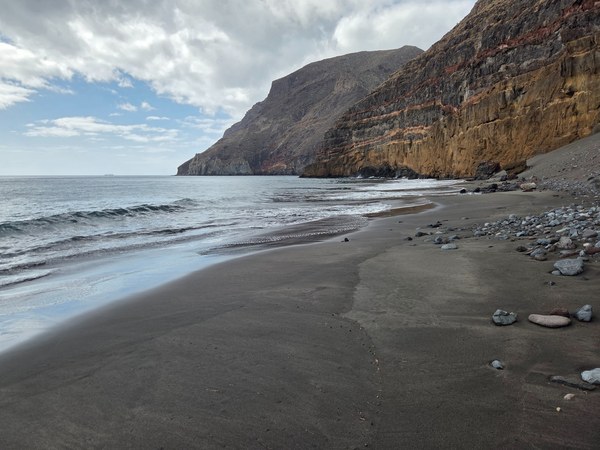 Plage d’Antequera à Tenerife, isolée au pied de hautes falaises, avec sable sombre, galets et mer tranquille.