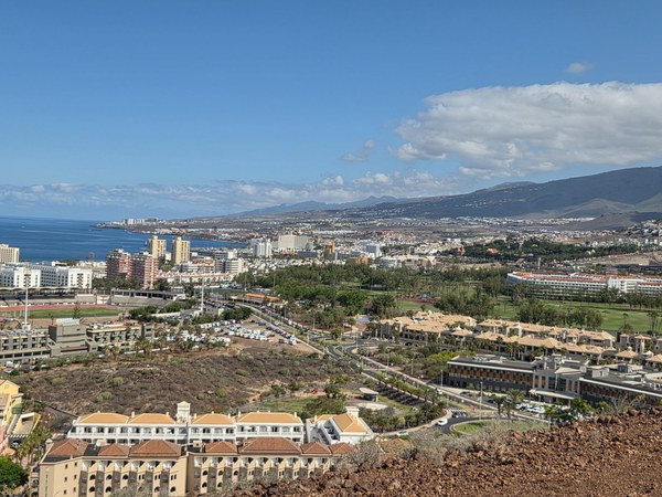 Vue sur Las Américas Vue panoramique sur Playa de las Américas à Tenerife, avec hôtels, littoral urbain et montagnes sous un ciel dégagé.