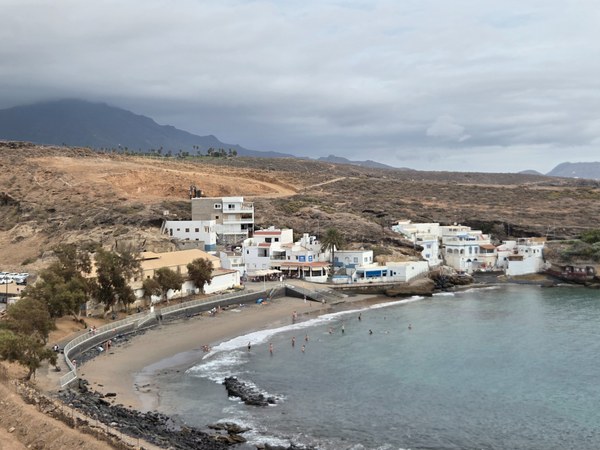 Petit bord de mer du Puertito à Tenerife, avec maisons blanches, plage tranquille et quelques baigneurs dans l’eau claire.