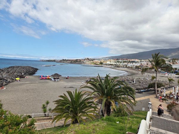 Panneau d’information sur la plage de Torviscas à Tenerife, posé sur le sable devant la mer au coucher du jour.