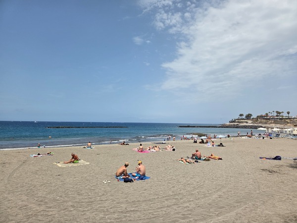 Playa Fañabé Vue large de Playa Fañabé avec sable clair, vacanciers allongés au soleil et mer paisible à Costa Adeje.