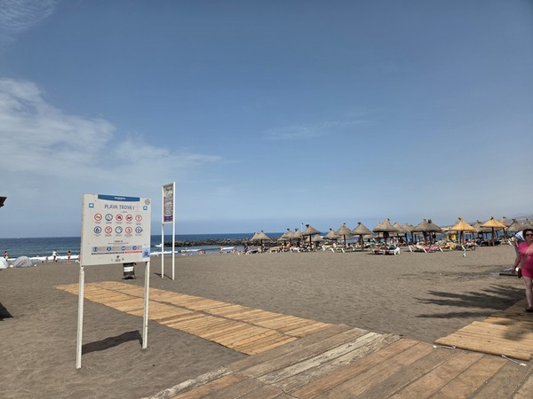 Playa Troya avec passerelles en bois, parasols en paille et zone de baignade à Costa Adeje.