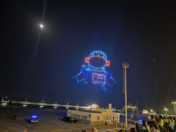 Spectacle nocturne de drones à Santa Cruz formant un astronaute lumineux dans le ciel.