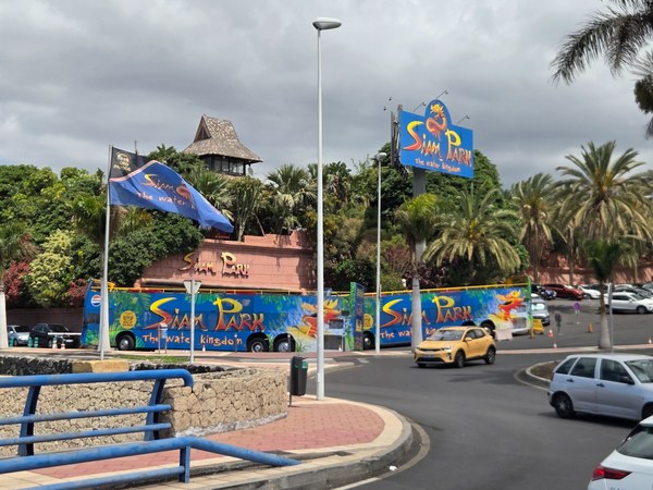 Vue extérieure de Siam Park à Tenerife, avec panneaux du parc aquatique, palmiers et route au premier plan.